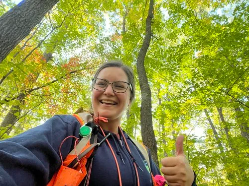 Chrissy Shaw outside in a forest smiling and giving the thumbs up.